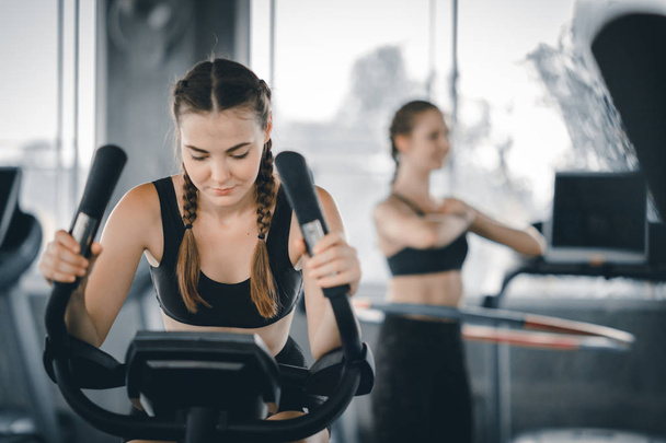 Attractive woman biking in the gym, exercising legs doing cardio workout cycling bikes. Fitness club with training exercise bikes. Fitness, Healthy, Sport, Lifestyle concept. - Photo, Image