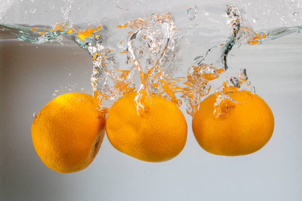 Three tangerine in water splash on white background - Photo, Image
