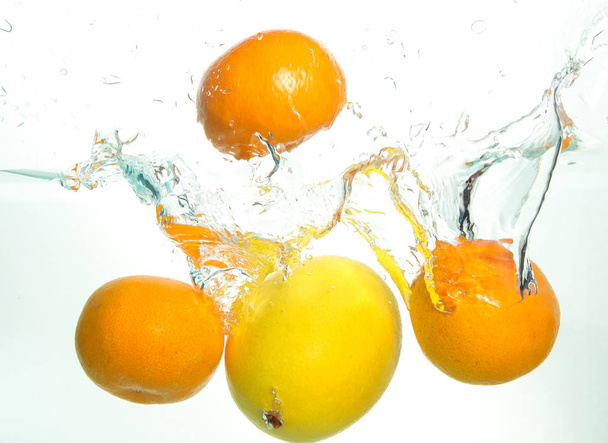 Tři oranžové a citrony ve vodě na bílém  - Fotografie, Obrázek