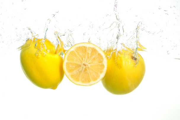 Tres limones salpican en agua sobre blanco
 - Foto, imagen
