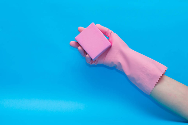 Hand in pink glove with pink sponge on blue background. - Fotografie, Obrázek