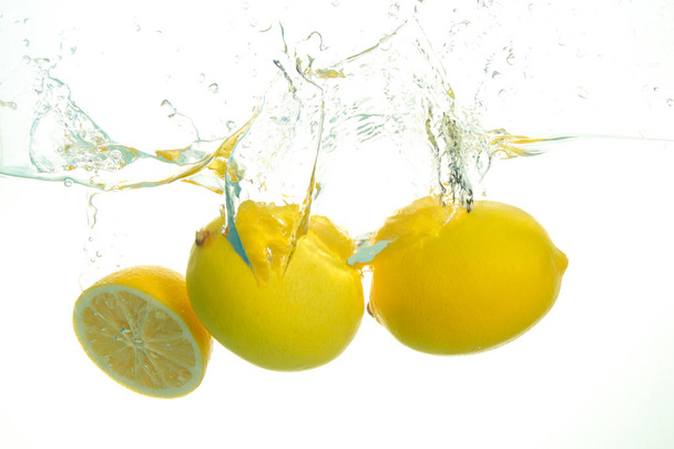 Three ripe lemons spash in water on white - Photo, Image