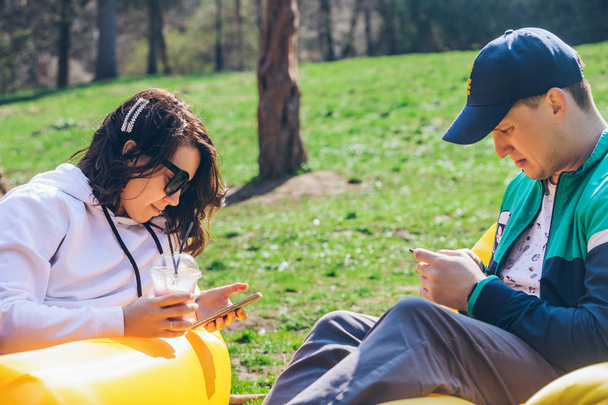 couple posé sur matelas gonflable dans le parc de la ville à la journée ensoleillée. parler et bavarder
 - Photo, image