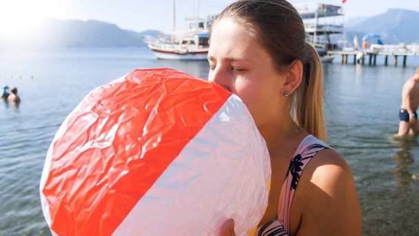 Portret van jonge vrouw met opblaasbare strandbal op zee - Foto, afbeelding