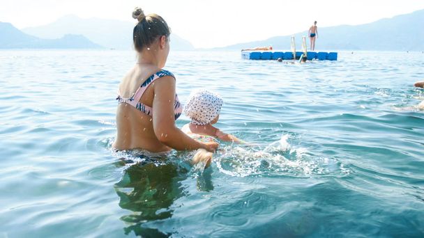 母親と一緒に海で泳いでいる小さな男の子。夏休みにくつろぐ家族 - 写真・画像
