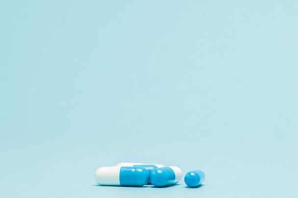 Lot of white capsules on a blue background. Medical background - Foto, imagen