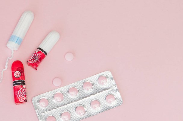 Sanitary pads and tampons and pills on pink background. Woman cr - Foto, afbeelding