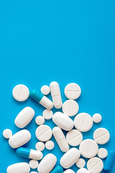 Scattered white pills on blue table. Mock up for special offers  - Photo, image