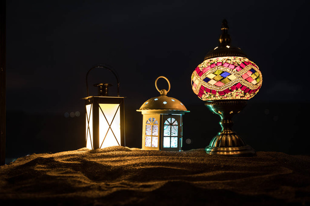 Ornamental Arabic lantern with burning candle glowing at night. Festive greeting card, invitation for Muslim holy month Ramadan Kareem. - Photo, Image