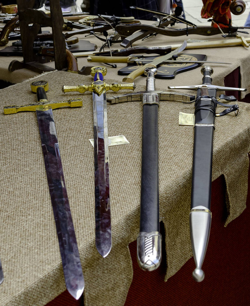 feria medieval con mercado y caballeros recreación espadas de juguete para la venta. Enfoque selectivo
 - Foto, Imagen