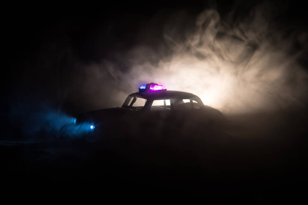 Politieauto 's' s nachts. Politieauto achtervolgt 's nachts een auto met mist achtergrond. 911 Noodhulpdiensten politie auto rijdt naar de plaats van de misdaad. Selectieve focus - Foto, afbeelding