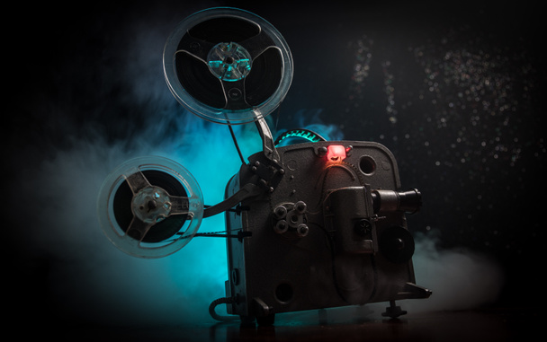 Stare zabytkowe projektor filmowy na ciemnym tle z mgłą i światłem. Koncepcja tworzenia filmów. Selektywna koncentracja - Zdjęcie, obraz