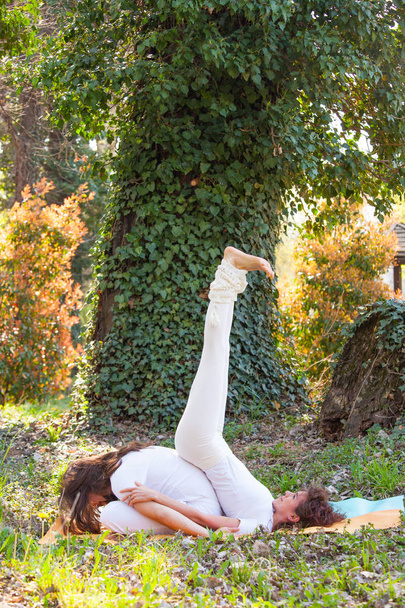 young man and woman practice partner yoga outdoor in wood summer - Foto, imagen