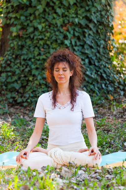 mujer joven en una posición meditativa de yoga día de verano en madera
  - Foto, Imagen