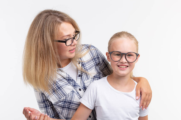 Happy young mother and laughing kid in fashion glasses have fun on white background - Фото, изображение