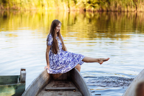 Lifestyle portrait of young beautiful woman sitting at motorboat. girl having fun at boat on the water. The girl sits on a boat in a lake - Foto, afbeelding