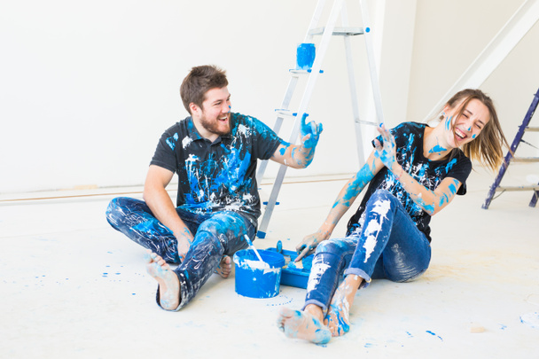 People, redecoration and relationship concept - Young funny couple doing renovation in new apartment and have fun at the break - Foto, afbeelding