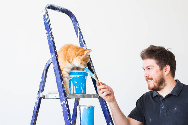 Ремонт, перепланировка и семейная концепция - молодой смешной человек и кошка во время ремонта в квартире
 - Фото, изображение