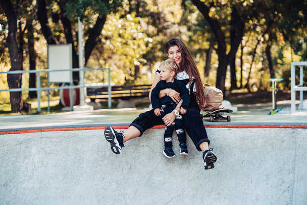 Mooie jonge hipster moeder en kleine zoon op het skatepark - Foto, afbeelding