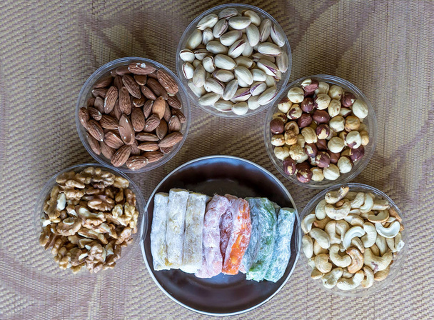 Traditional Turkish Delight. Oriental dessert on a  plate. Isolated on background. Eastern delicacy sweets. Healthy food. Nuts mix assortment. Collection of different legumes for image close up nuts, pistachios, almond, cashew nuts, peanut, walnut on - Photo, Image