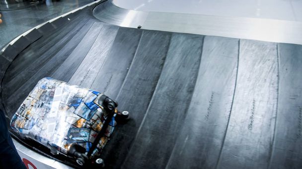 Closeup image of suitcase lying on luggage claim line at modern airport terminal - Photo, Image