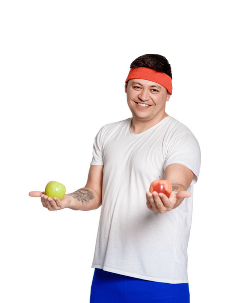 Tlustý Muž na bílém pozadí s jablkem v dlaních. člověk si vybral zdravý životní styl.  - Fotografie, Obrázek