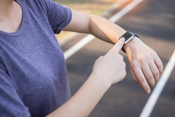 Kadın onun akıllı saatler bakarak kullanarak sabah egzersiz - Fotoğraf, Görsel