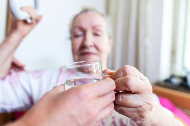 Une jeune femme donne un verre d'eau à une vieille femme
 - Photo, image