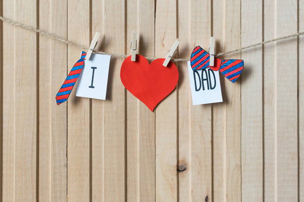 Apák napi koncepció. Üzenet papír szívvel, nyakkendő és csokornyakkendő lóg csap át könnyű fából készült fórumon. Copyspace (másolat). Szabad hely a szöveghez. boldog születésnapot - Fotó, kép