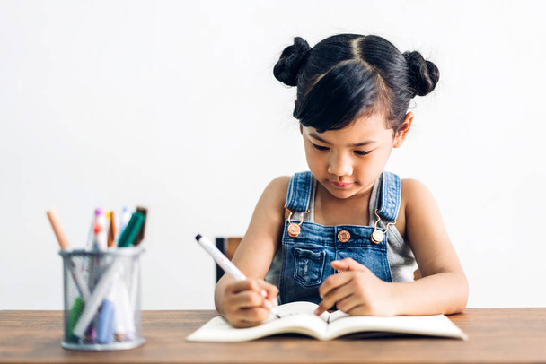 Enfant de l'école petite fille apprenant et écrivant dans un cahier avec stylo
 - Photo, image