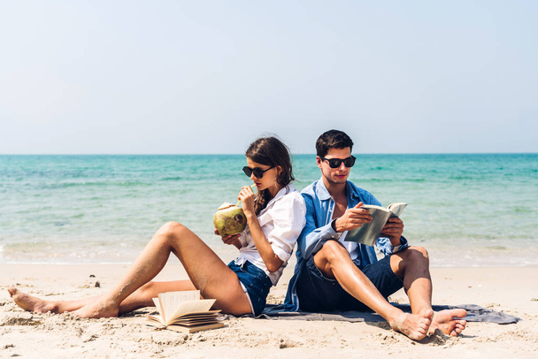 Young couple drinking coconut juice and reading a book on the tr - Photo, Image