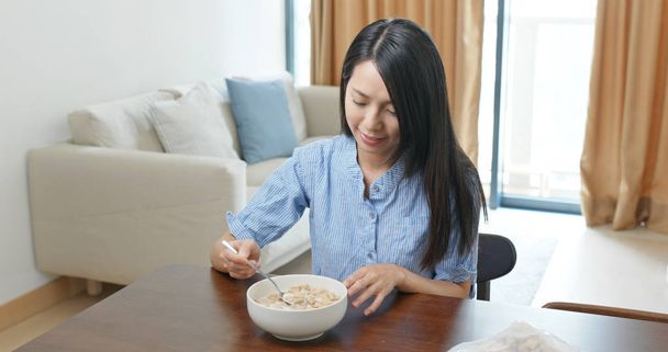 Vrouw eet ontbijtgranen thuis - Foto, afbeelding