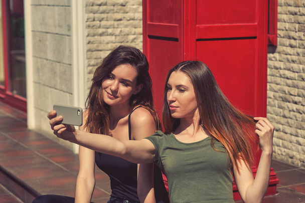 Young girls take a selfie with your smartphone on the street . Modern technologies in everyday life - Foto, Imagen
