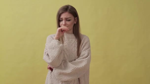 Young disappointed girl standing isolated over yellow background while looking camera - Video, Çekim