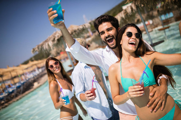 Grupa szczęśliwych przyjaciół bawiących się tańcząc na basenie z koktajlami - Zdjęcie, obraz