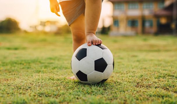 Sportowy obraz akcji grupy dzieci grających w piłkę nożną do ćwiczeń w zielonym polu trawy. - Zdjęcie, obraz
