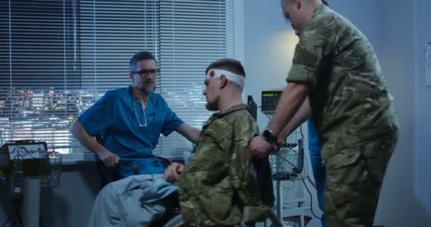 Στρατιώτης που κάθεται σε αναπηρικό αμαξίδιο μεταξύ γιατρού και νοσοκόμας - Πλάνα, βίντεο