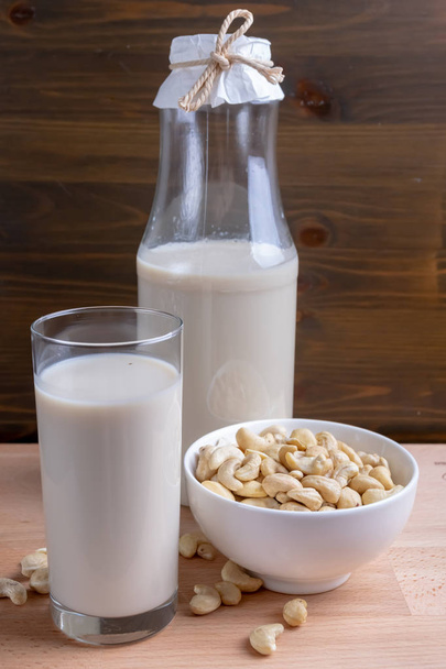 Anacardi latte in vetro e anacardi biologici su sfondo di legno, Latte alternativo
 - Foto, immagini