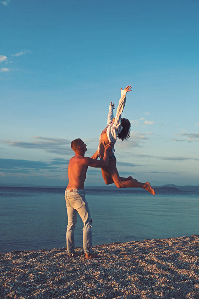 Sexy woman and man jump on sand. Happy family on valentines day. Love relations of naked couple at sea. Couple in love with sexy body relax on beach. Summer holidays and paradise travel vacation. - Foto, imagen