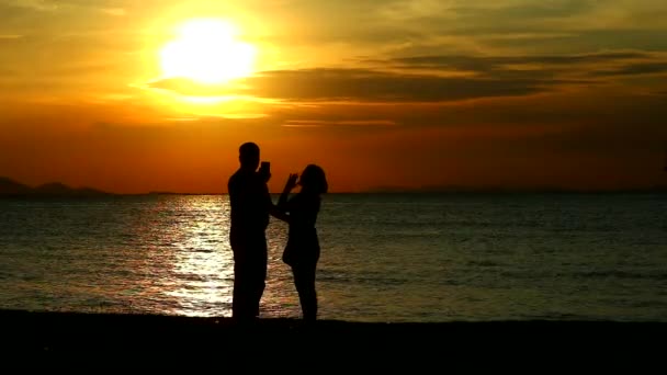 Couple amant prendre selfies tandis que le coucher du soleil sur la mer
 - Séquence, vidéo