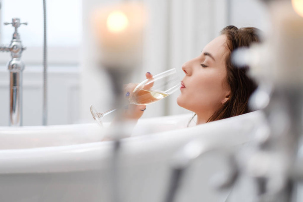 Femme couchée dans un bain avec une coupe de champagne
 - Photo, image
