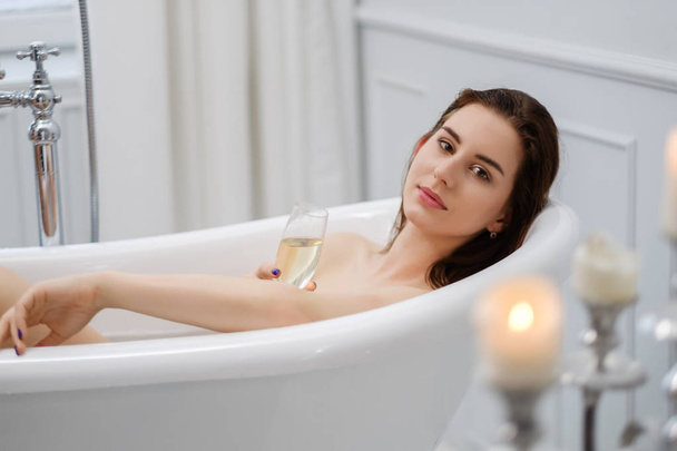 Woman laying in a bath with glass of champagne - Fotó, kép