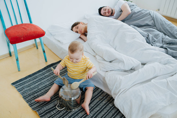 Cute little son trying to wake up his parents. - Foto, immagini