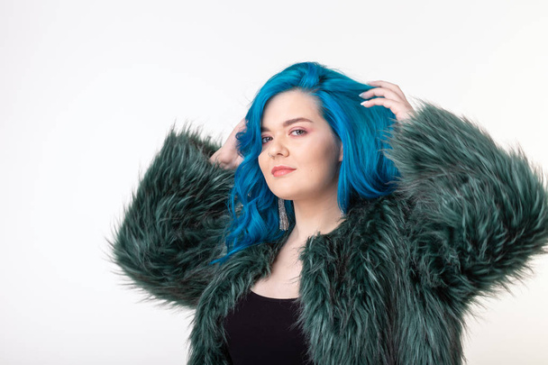 Animal protection, fashion and hair concept - beautiful girl dressed in artificial fur coat with blue hair standing on white background - Photo, Image