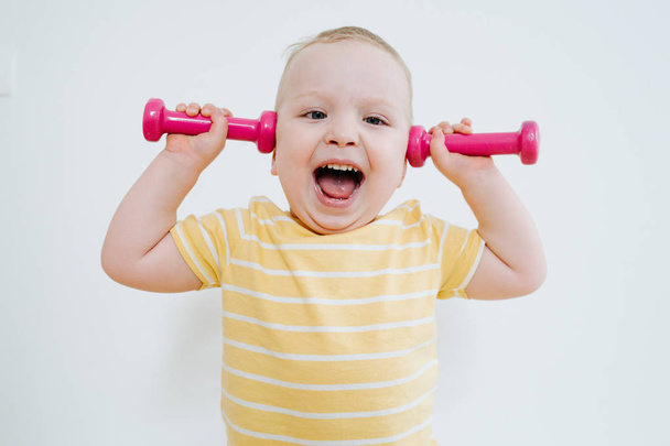 Portrait of little baby going to play with dumbbells - Foto, imagen