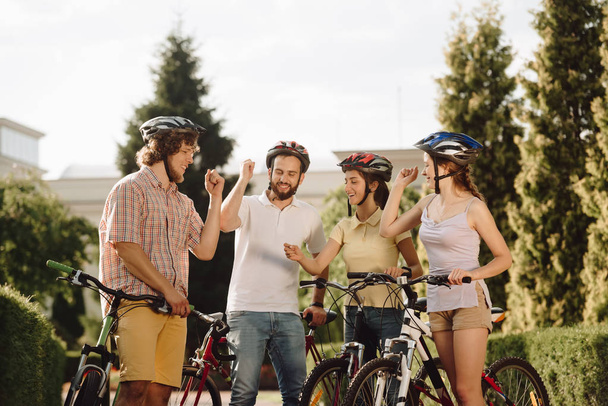 Молоді усміхнені велосипедисти відпочивають на відкритому повітрі
. - Фото, зображення