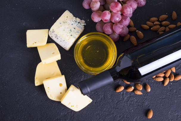 Snacks with wine - bottle, various types of cheeses, figs, nuts, honey, grapes - Foto, imagen