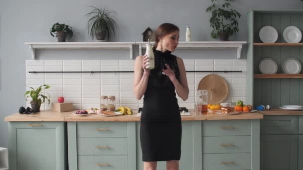 Elegant brunette woman drinking smoothie in the kitchen and dancing. - Materiał filmowy, wideo