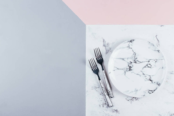 Empty ceramic marble plate and cutlery on tricolor pink gray marble background. Copy space. Menu Recipe Concept - Photo, Image