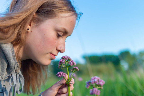Una joven huele una fragante flor silvestre
 - Foto, imagen